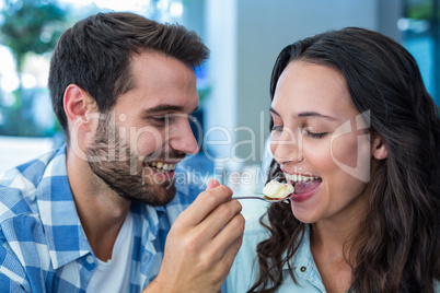 Young happy couple feeding each other with cake