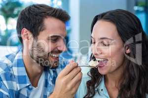 Young happy couple feeding each other with cake