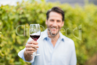 Young happy man smiling at camera and holding a glass of wine