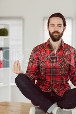 Hipster businessman meditating at his desk