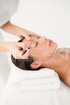 Woman using tweezers on patient eyebrow