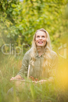 Blonde winegrower holding a red grapes basket