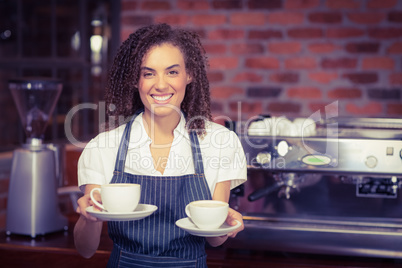 Smiling barista holding two cups of coffee