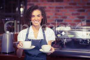 Smiling barista holding two cups of coffee
