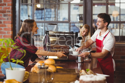 A smiling barista serving a client