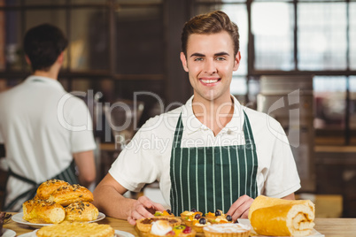 Smiling waiter tidying up the pastries