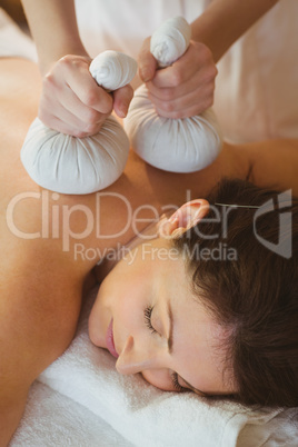 Young woman getting herbal compress massage