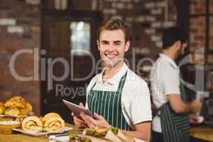 Smiling waiter holding a digital tablet