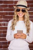 Gorgeous blonde hipster with sunglasses using smartphone