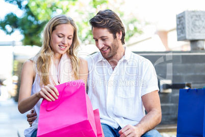 Smiling couple sitting and looking into shopping bags