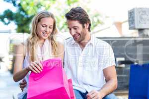 Smiling couple sitting and looking into shopping bags