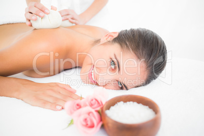 Beautiful brunette enjoying a herbal compress massage