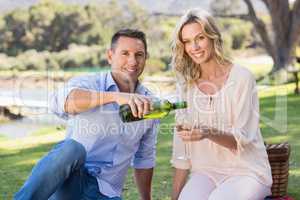 Portrait of smiling couple sitting and pouring wine in glass