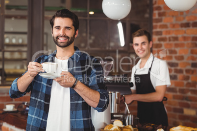 Smiling hipster drinking coffee in front of barista