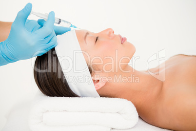 Woman receiving botox injection on her forehead