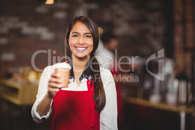 Smiling waitress handing a take-away mug