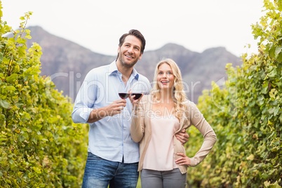 Young happy couple holding a glass of wine and looking in the di