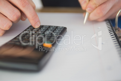 Businessman using a calculator and writing