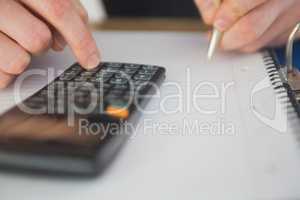 Businessman using a calculator and writing