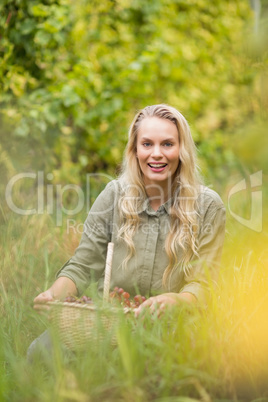 Blonde winegrower holding a red grapes basket