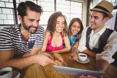 Laughing friends pointing and looking at tablet computer