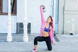 Athletic woman exercising turkish get up with kettlebell
