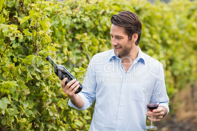 Young happy man looking at wine bottle