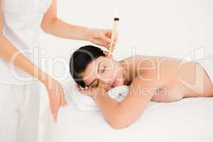 Beautiful woman receiving ear candle treatment at spa center