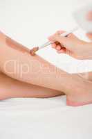 Therapist waxing womans leg at spa center