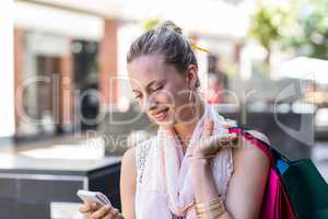 Smiling woman with shopping bags calling with mobile phone