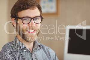 Happy hipster sitting at his desk