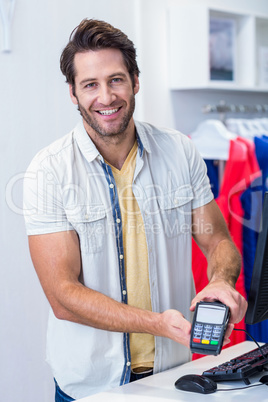 Smiling cashier showing credit card reader