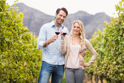 Young happy couple holding a glass of wine and looking at camera