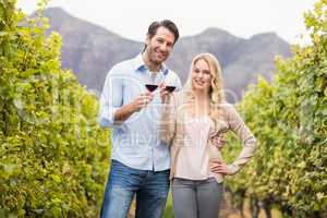 Young happy couple holding a glass of wine and looking at camera