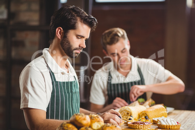 Concentrated waiters tidying up the pastries