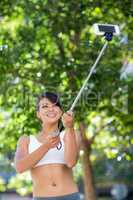 Smiling athletic woman taking selfies with selfiestick