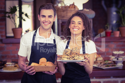 Smiling waiter and waitress holding bread bun