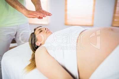 Close up view of pregnant woman getting reiki treatment