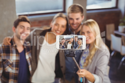Smiling friends taking selfies with selfiestick