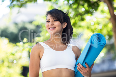 Smiling athletic woman carrying yoga mat