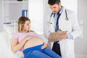 Doctor giving advice to lying pregnant patient