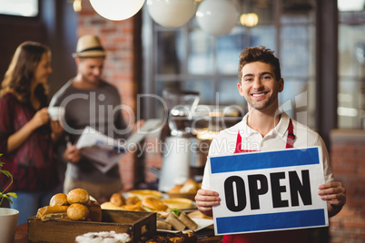 Smiling waiter posing with open sign