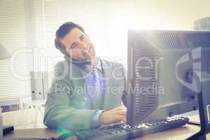 Businessman having phone call while using his computer