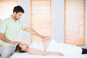 Relaxed pregnant woman getting reiki treatment