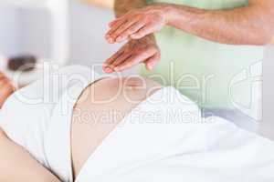 Close up view of pregnant woman getting reiki treatment