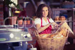 Smiling waitress putting bread in a paper bag