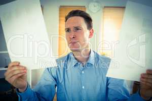 Serious businessman holding two paper sheets
