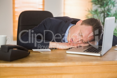 Exhausted businessman sleeping on his laptop