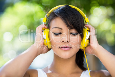 Athletic woman wearing yellow headphones and enjoying music with