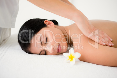 Pretty brunette enjoying a massage smelling flower at camera